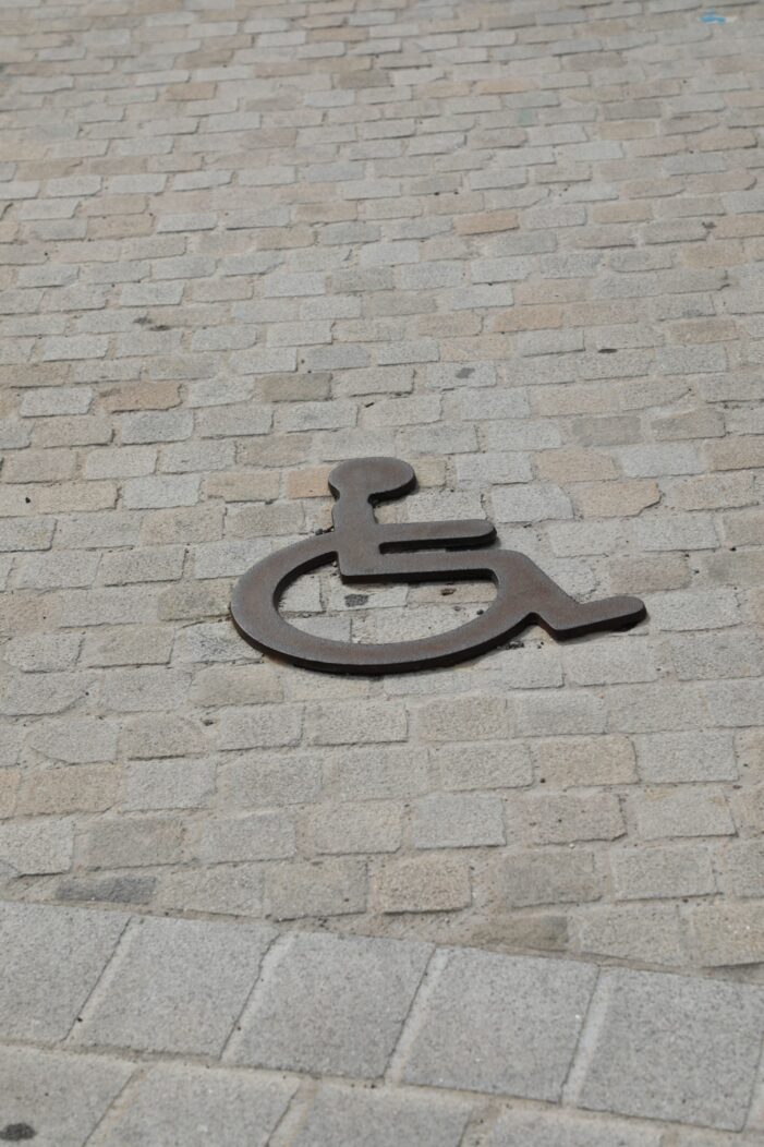 Logo PMR en fonte d'acier sur une place de parking réservée en centre-ville.